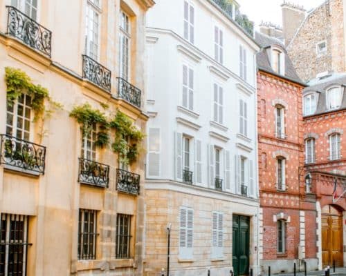 Une rue pittoresque d’une ville française, bordée d’immeubles anciens au charme typiquement parisien ou haussmannien.