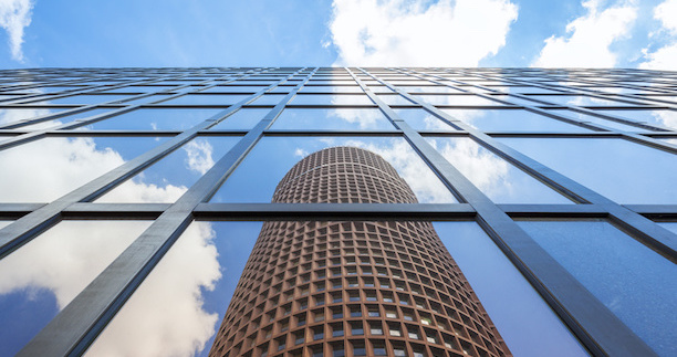 La réflexion d’une tour emblématique dans la façade vitrée d’un immeuble moderne