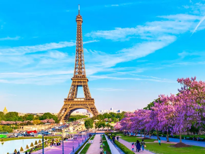 Appartement parisien moderne en arrière-plan avec un marqueur géographique sur la carte de Paris au premier plan, symbolisant le choix stratégique des quartiers pour investir à distance en 2026