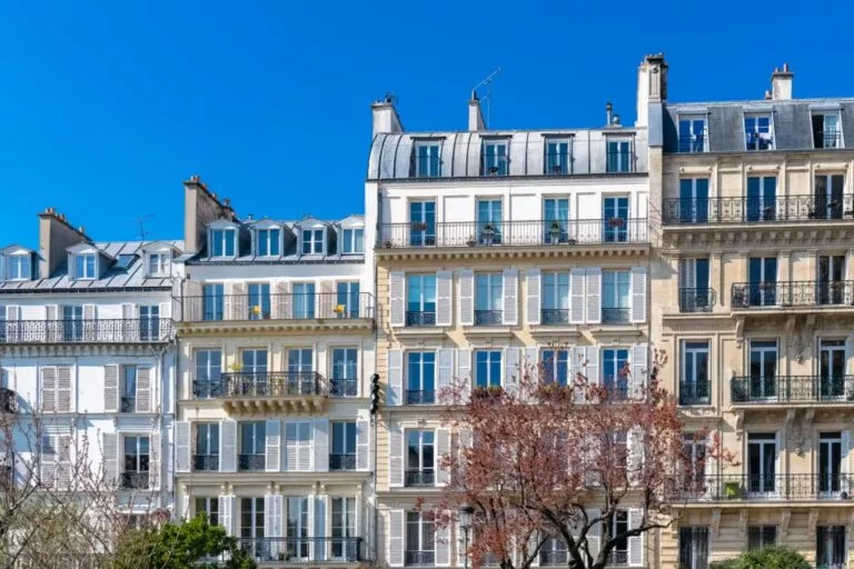 Une rangée d’immeubles haussmanniens typiques de Paris, baignés par un ciel bleu éclatant