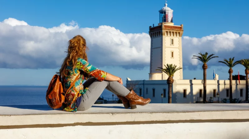 Une femme assise sur le bord d'une muraille se demandant dans quoi investir au maroc .