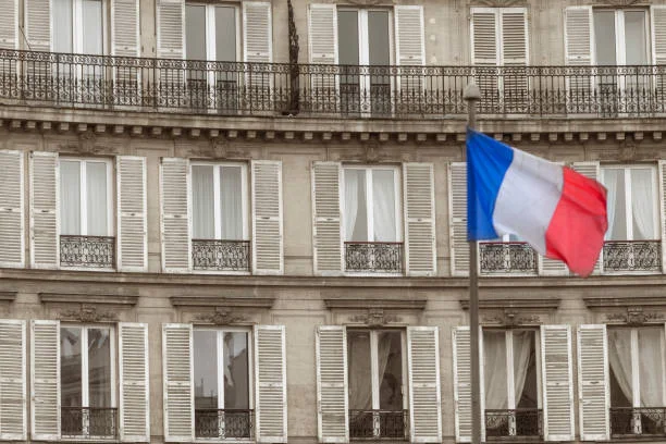 Image d'un bâtiment avec un drapeau de la France illustrant la situationn immobilière en France avec Emmanuel Macron