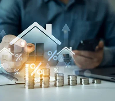 Une personne travaillant sur un ordinateur portable, entourée de documents financiers, planifie le financement de son logement depuis l’étranger