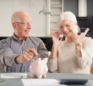 Un retraité devant son ordinateur avec des papiers administratifs Homme retraité consultant sa déclaration fiscale en ligne depuis l’étranger